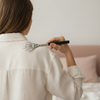Femme de dos en chemise de lin utilisant un gratte-dos télescopique en acier inoxydable sur l'épaule